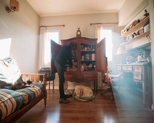 A person comfortably arranging items on a living room shelf
